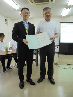 阿部裕行多摩市長に報告書手渡す馬場明仁さん(経営情報学部2年)