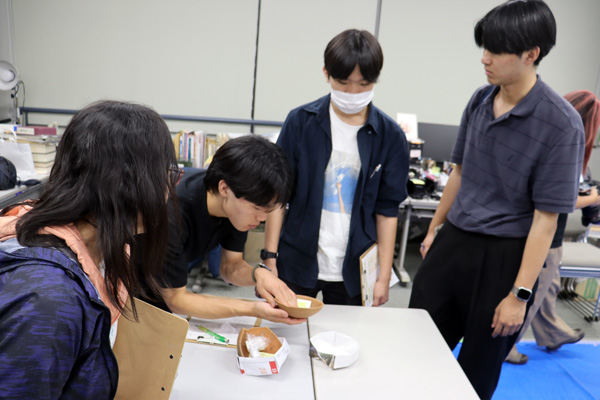 発掘された縄文土器の修復・復元(再生)作業場を見学する学生たち